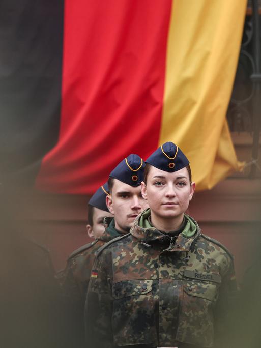 Eine Soldatin steht vor einer Deutschlandflagge. Rund 160 Rekrutinnen und Rekruten des Luftwaffenausbildungsbataillons aus Roth und des Heimatschutzregiments 5 aus Hessen mit Sitz in Thüringen legten ihren Diensteid ab. Eine Soldatin steht vor einer Deutschlandflagge. Rund 160 Rekrutinnen und Rekruten des Luftwaffenausbildungsbataillons aus Roth und des Heimatschutzregiments 5 aus Hessen mit Sitz in Thüringen legten ihren Diensteid ab.