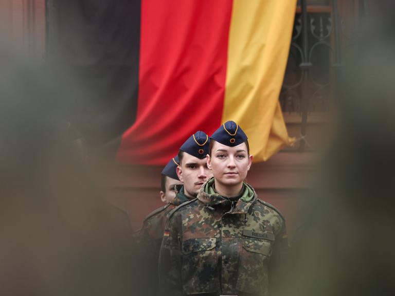 Eine Soldatin steht vor einer Deutschlandflagge. Rund 160 Rekrutinnen und Rekruten des Luftwaffenausbildungsbataillons aus Roth und des Heimatschutzregiments 5 aus Hessen mit Sitz in Thüringen legten ihren Diensteid ab. Eine Soldatin steht vor einer Deutschlandflagge. Rund 160 Rekrutinnen und Rekruten des Luftwaffenausbildungsbataillons aus Roth und des Heimatschutzregiments 5 aus Hessen mit Sitz in Thüringen legten ihren Diensteid ab.