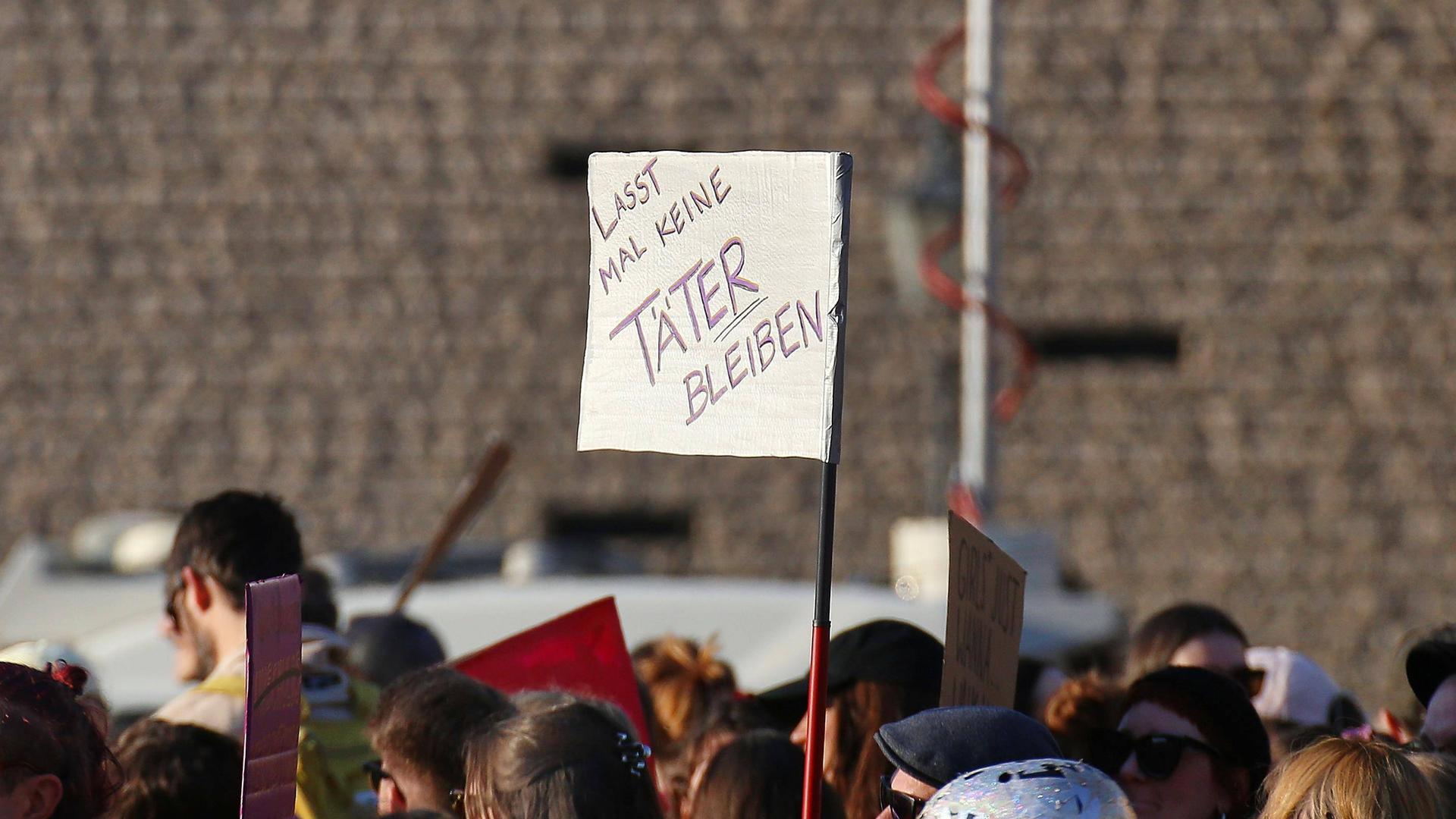 Bei einer Demo wird ein Schild mit der Aufschrift hochgehalten: "Lass mal keine Täter bleiben".