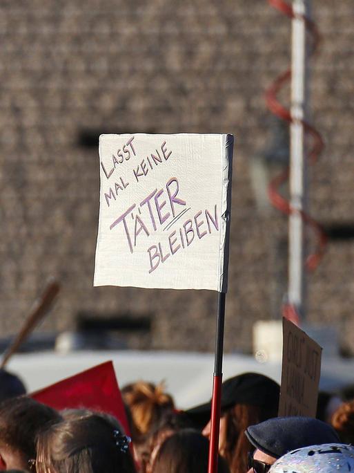 Bei einer Demo wird ein Schild mit der Aufschrift hochgehalten: "Lass mal keine Täter bleiben".