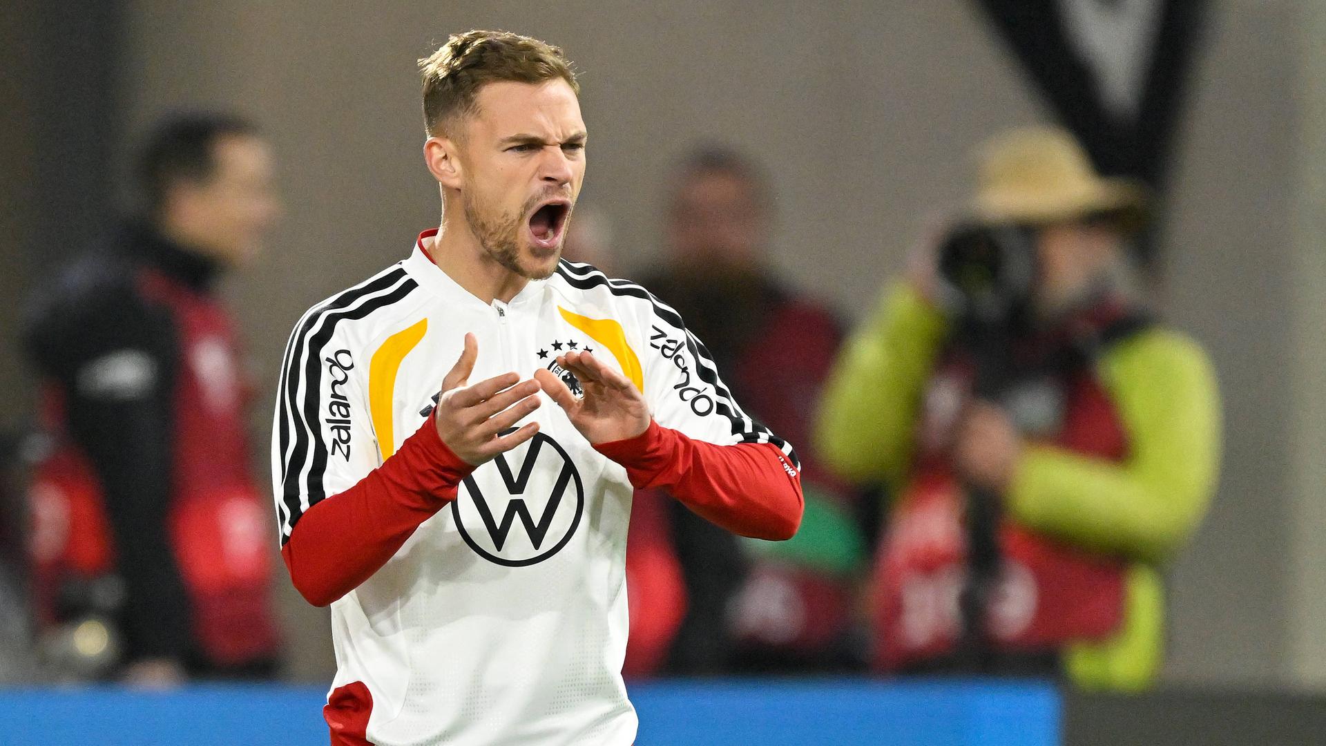 Fußballspieler Joshua Kimmich steht bei einem Fußball-Länderspiel am Spielfeldrand und gestikuliert. Fußballspieler Joshua Kimmich steht bei einem Fußball-Länderspiel am Spielfeldrand und gestikuliert.