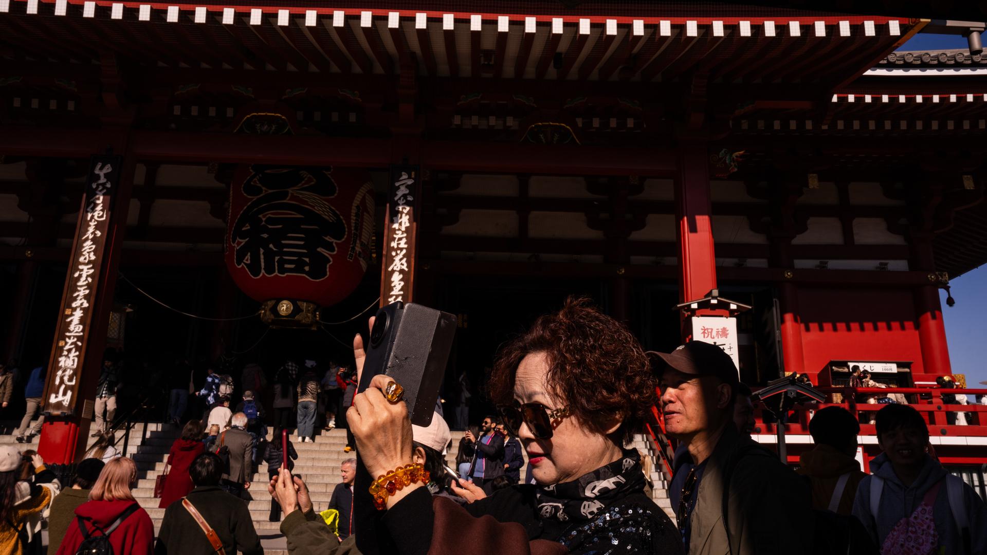 Chinesische Touristen machen vor dem Sensoji Tempel bei Tokio Fotos mit ihren Smartphones
