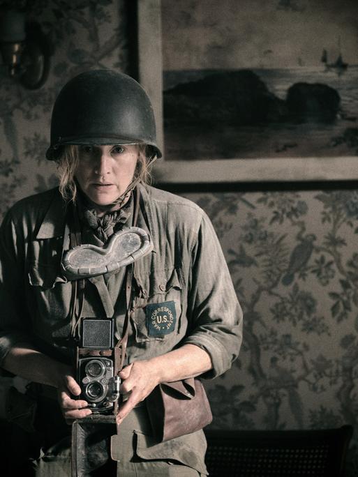 Kate Winslet mit Uniform und Kamera in einer Szene des Films "Die Fotografin".