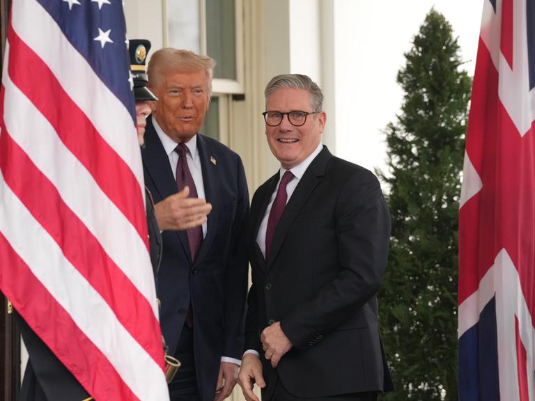 Großbritanniens Ministerpräsident Keir Starmer steht zusammen mit Donald Trump zwischen einer US-Flagge und dem Union Jack auf der Terasse des Weißen Hauses