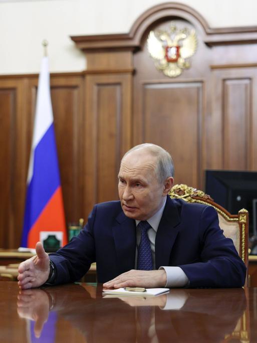 Russlands Präsident Wladimir Putin sitzt an seinem Schreibtisch und macht eine Handbewegung