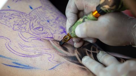 Ein Tätowierer sticht ein Tattoo