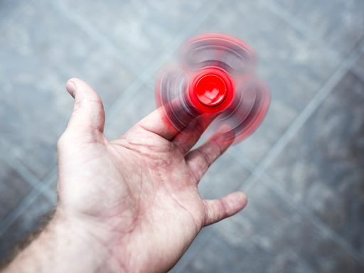 Ein roter Figest Spinner dreht sich schnell in der Hand einer erwachsenen Person.