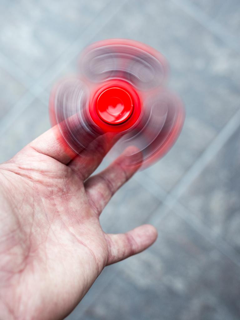Ein roter Figest Spinner dreht sich schnell in der Hand einer erwachsenen Person.