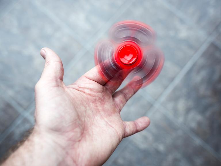 Ein roter Figest Spinner dreht sich schnell in der Hand einer erwachsenen Person. Ein roter Figest Spinner dreht sich schnell in der Hand einer erwachsenen Person.