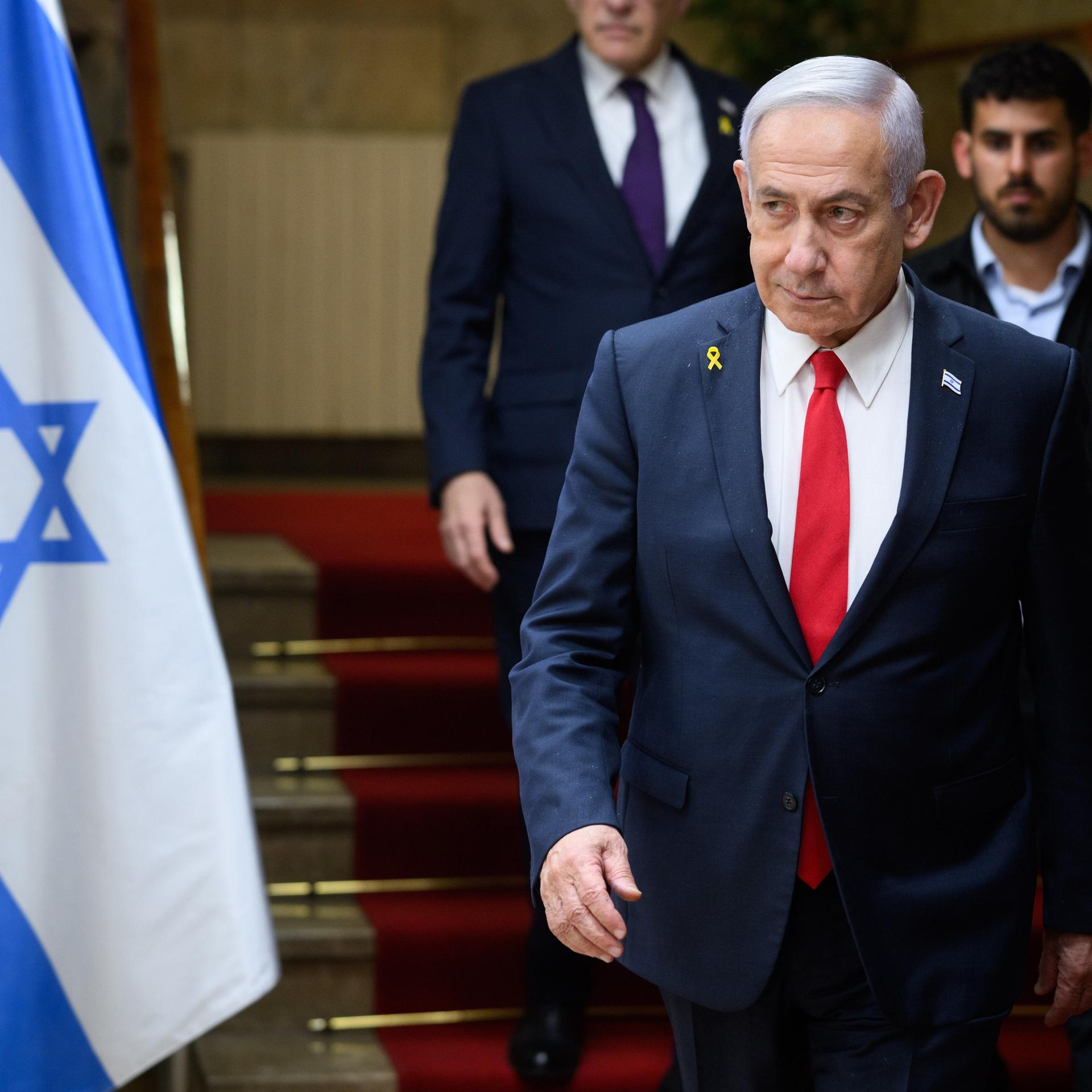 Benjamin Netanjahu, Ministerpräsident von Israel, läuft eine Treppe hinunter, ein Personenschützer ist hinter zu sehen. Neben ihm ist die Flagge Israels zu erkennen. Benjamin Netanjahu, Ministerpräsident von Israel, läuft eine Treppe hinunter, ein Personenschützer ist hinter zu sehen. Neben ihm ist die Flagge Israels zu erkennen.