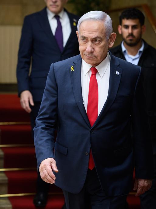 Benjamin Netanjahu, Ministerpräsident von Israel, läuft eine Treppe hinunter, ein Personenschützer ist hinter zu sehen. Neben ihm ist die Flagge Israels zu erkennen.