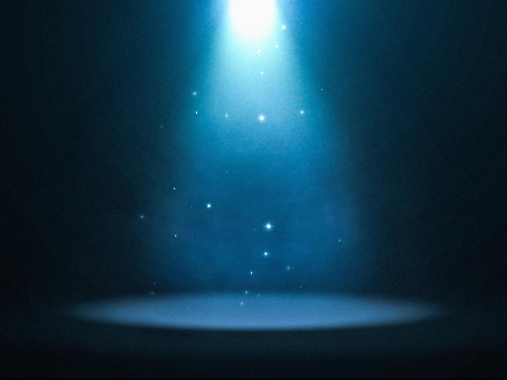 Ein bläulich strahlendes Spotlight ist auf eine leere Bühne gerichtet.