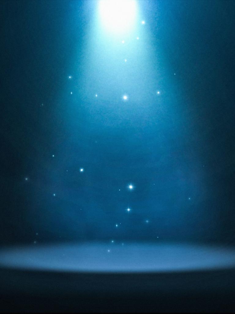 Ein bläulich strahlendes Spotlight ist auf eine leere Bühne gerichtet.