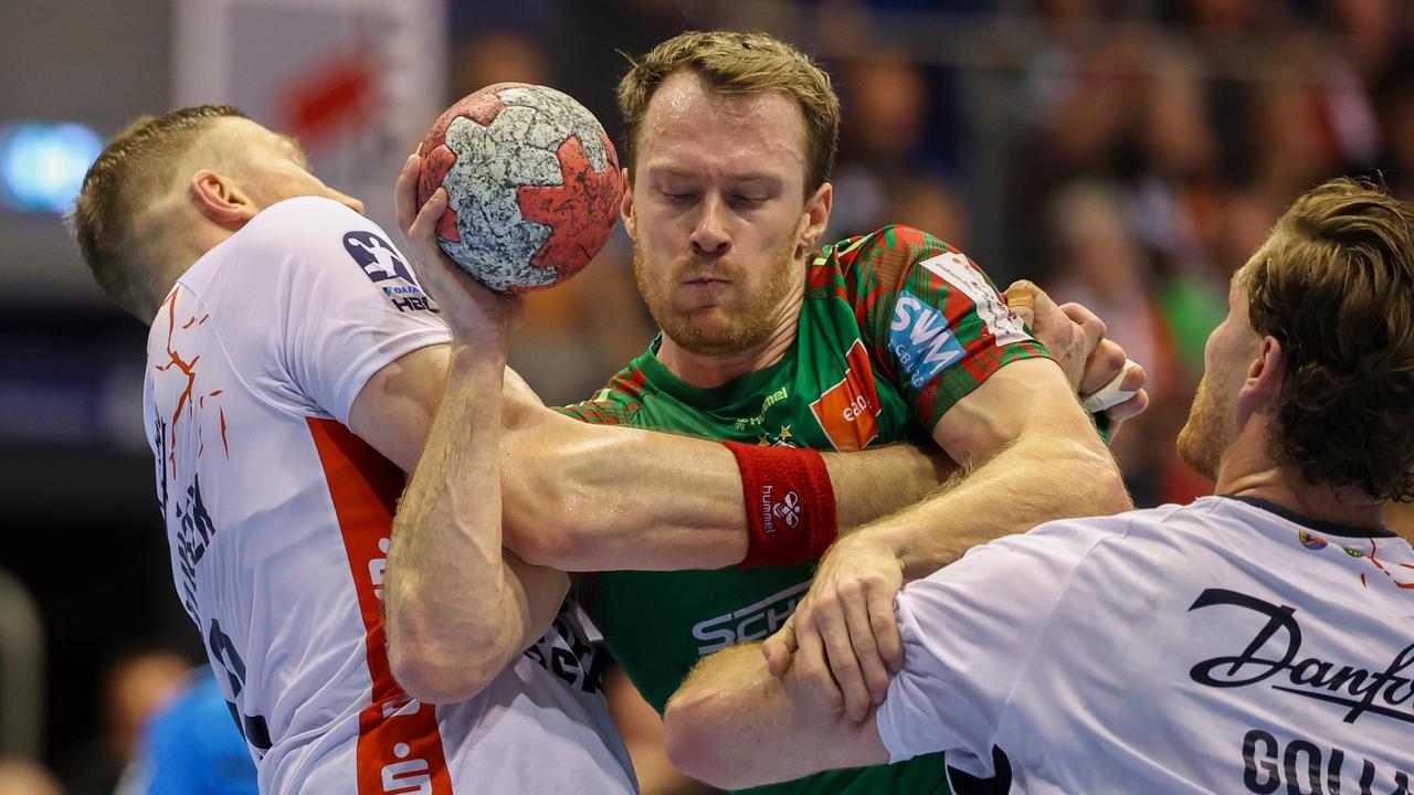 Drei Handballspieler kämpfen um den Ball.