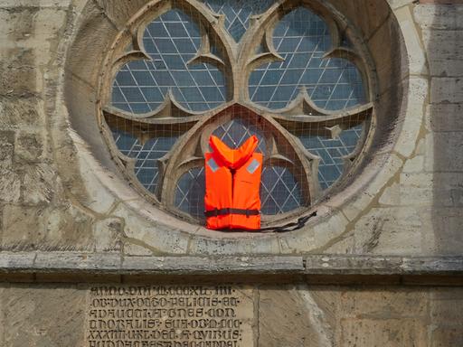 Eine Rettungsweste wird in einem Fenster der Kathedrale In Braunschweig gezeigt,  als Unterstützung für Flüchtlinge.