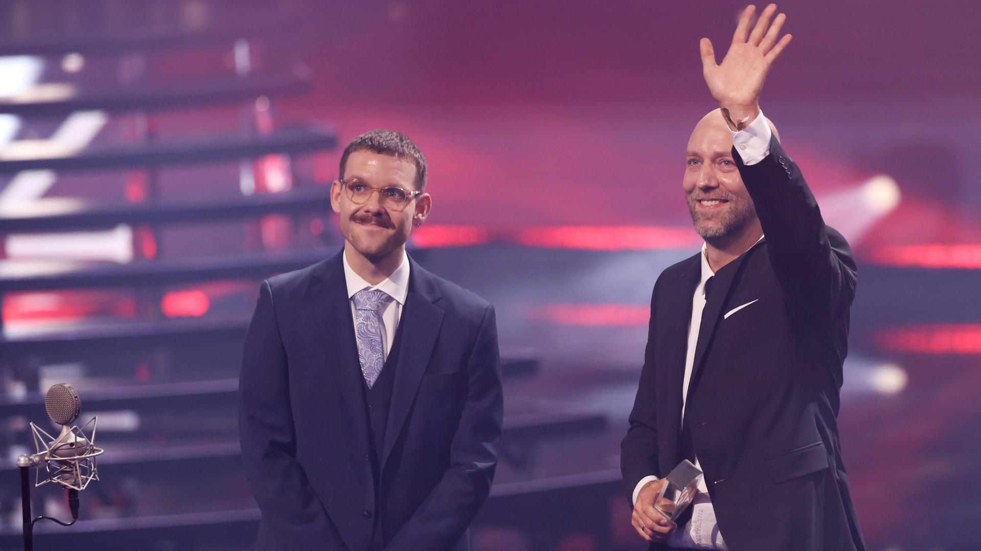 Jannik Stein (l) und Thorsten Christes vom Sender TOGGO Radio stehen bei der Verleihung des Deutschen Radiopreises 2025 auf der Bühne und freuen sich.