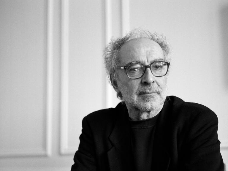 Schwarz-weiß Porträt von  Jean-Luc Godard im April 2001. Mit gefalteten Händen schaut er konzentriert Richtung Kamera.