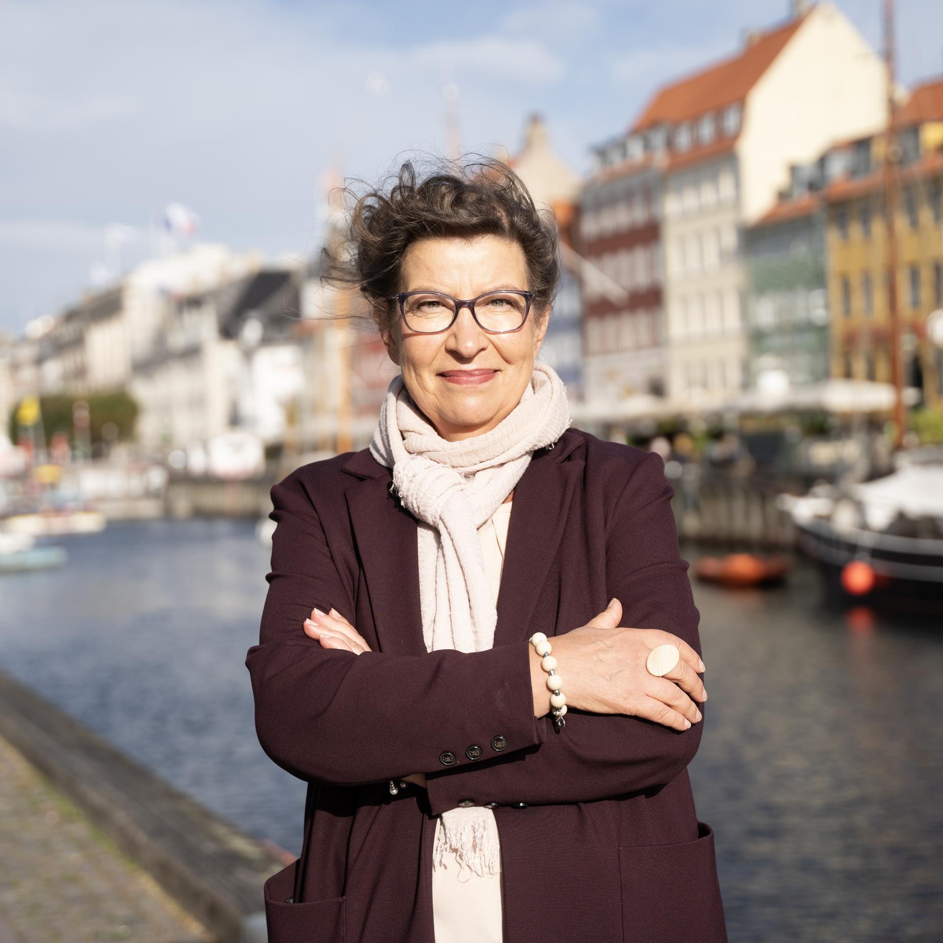 Die Exekutivdirektorin der Europäischen Umweltagentur (EEA), Leena Ylä-Mononen, steht mit verschränkten Armen vor einem Kanal und lächelt.