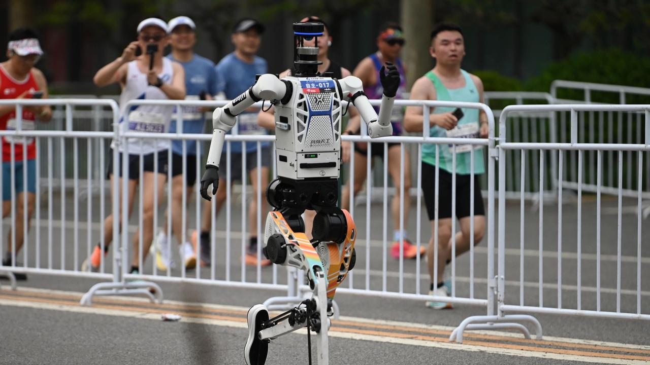 Zu sehen ist ein Roboter in Peking. Er läuft auf einer abgesperrten Strecke.