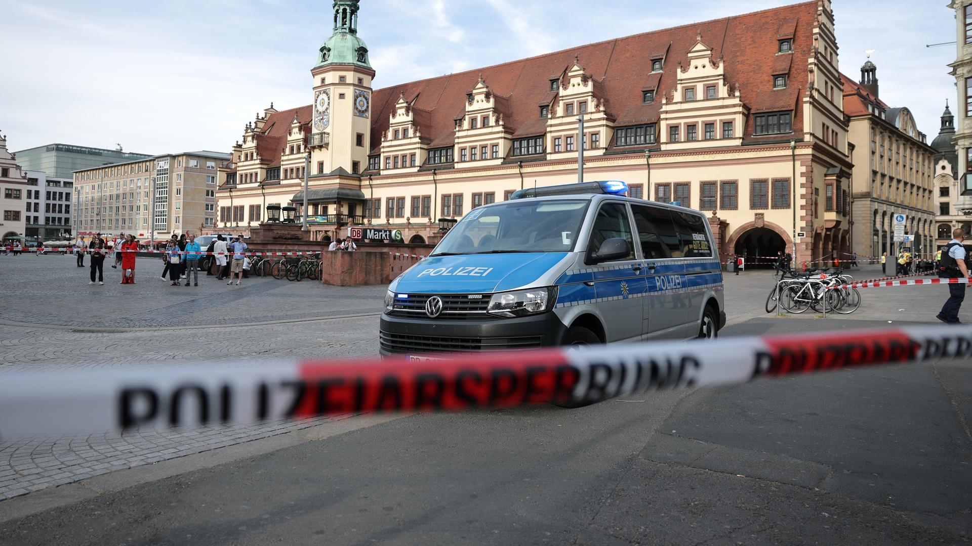Ein Polizeiwagen parkt hinter einer Polizeiabsperrung an der Stelle, wo ein Auto in eine Menschengruppe gefahren ist.