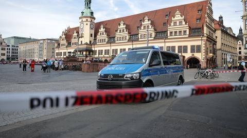 Ein Polizeiwagen parkt hinter einer Polizeiabsperrung an der Stelle, wo ein Auto in eine Menschengruppe gefahren ist.