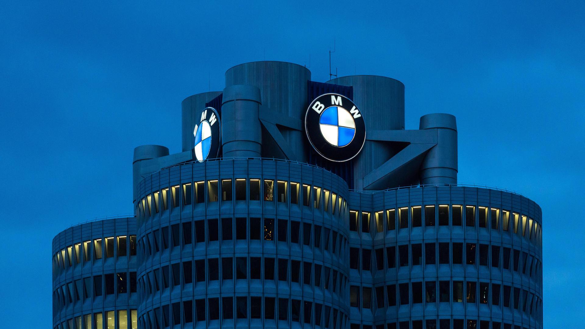 Der BMW-"Vierzylinder", das Hauptverwaltungsgebäude und Wahrzeichen des Fahrzeugherstellers BMW in München bei Nacht mit dem leuchtenden Logo des Autobauers. 