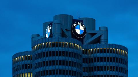 Der BMW-Vierzylinder, das Hauptverwaltungsgebäude und Wahrzeichen des Fahrzeugherstellers BMW in München bei Nacht mit dem leuchtenden Logo des Autobauers.