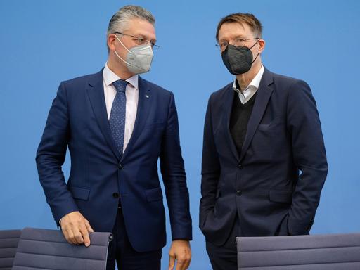 Bei einer Pressekonferenz im Jahr 2022 stehen der damalige Präsident des Robert-Koch-Instituts Lothar H. Wieler zusammen mit Bundesgesundheitsminister Karl Lauterbach (SPD) zusammen und unterhalten sich. Beide tragen FFP2-Masken.