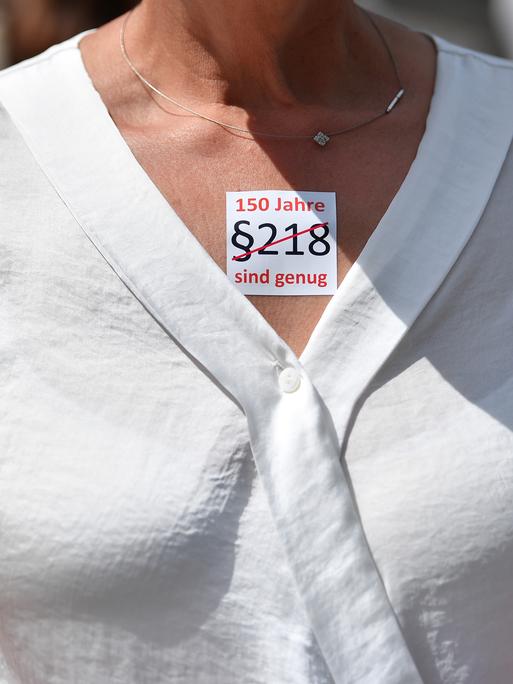 "§218. 150 Jahre sind genug" steht auf dem Sticker einer Demonstrantin, der auf ihrem Dekolleté klebt.