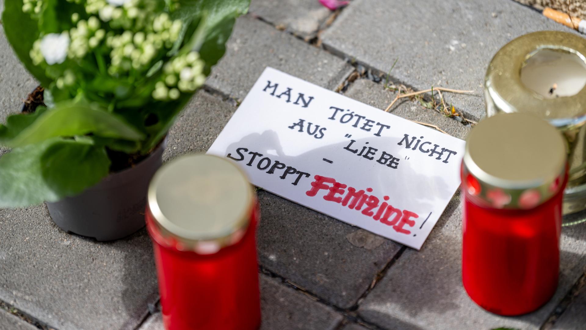 Blumen und Kerzen liegen nach einem tödlichen Messerangriff vor einem Hauseingang in Berlin-Friedrichsfelde neben einem Zettel mit der Aufschrift "Man tötet nicht aus Liebe - Stoppt Femizide".