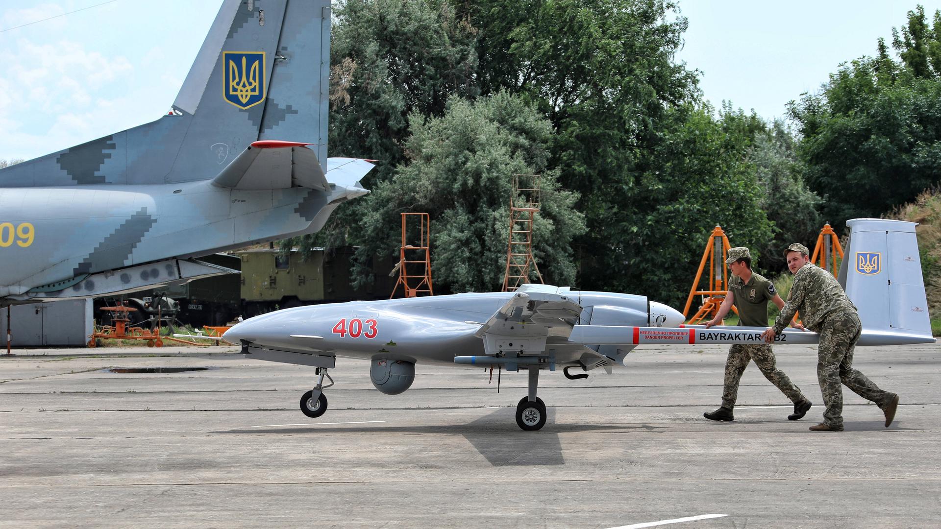 Ukrainische Soldaten rollen auf einem Militärflugplatz eine Drohne zu einem Flugzeug. Ukrainische Soldaten rollen auf einem Militärflugplatz eine Drohne zu einem Flugzeug.
