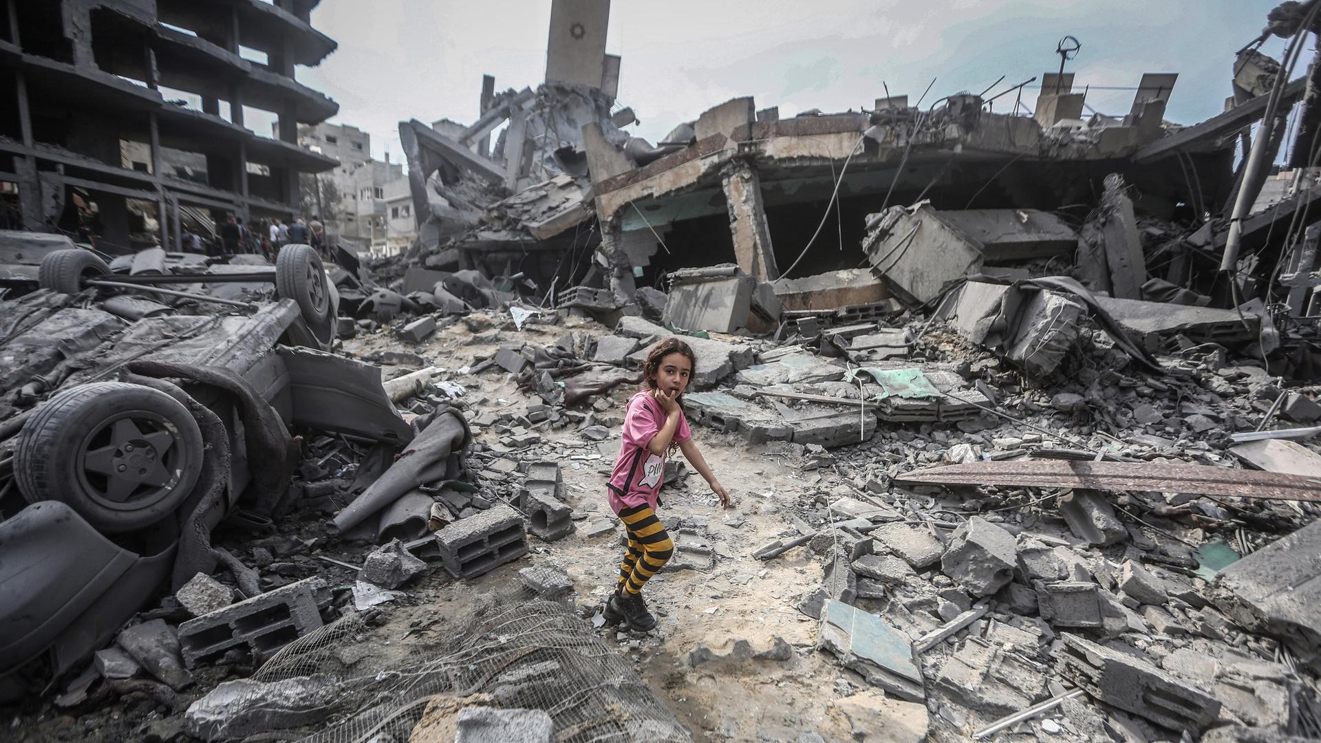 Ein palästinensisches Mädchen läuft über Trümmer von durch israelische Luftangriffe zerstörten Gebäuden. 