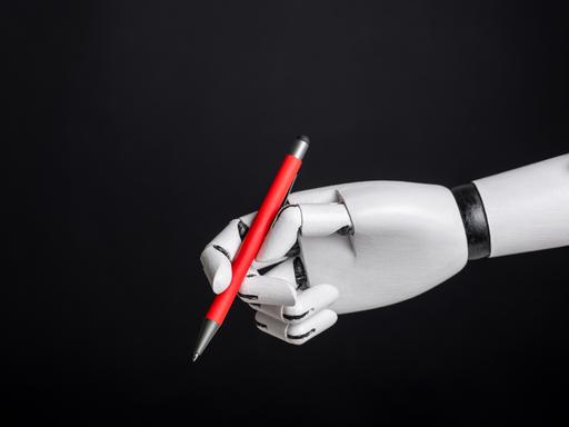 Eine Roboterhand hält vor einem schwarzen Hintergrund einen roten Stift.