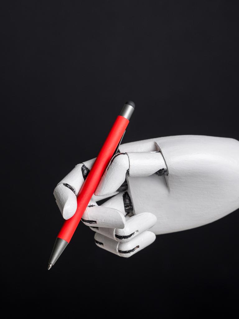 Eine Roboterhand hält vor einem schwarzen Hintergrund einen roten Stift.