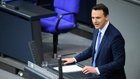 Reddig im dunklen Jackett steht am Rednerpult des Bundestags und sagt etwas.