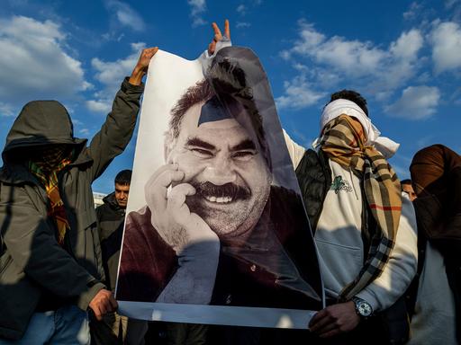 Verhüllte Männer halten ein Porträt von Abdullah Ocalan in die Höhe