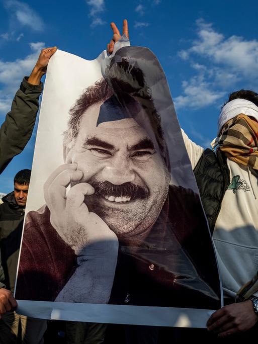 Verhüllte Männer halten ein Porträt von Abdullah Ocalan in die Höhe