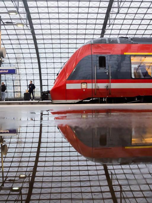 Ein Regionalzug fährt am Berliner Hauptbahnhof ein. Der Zug und die Halle spiegeln sich in einer Pfütze. (29.10.2023)