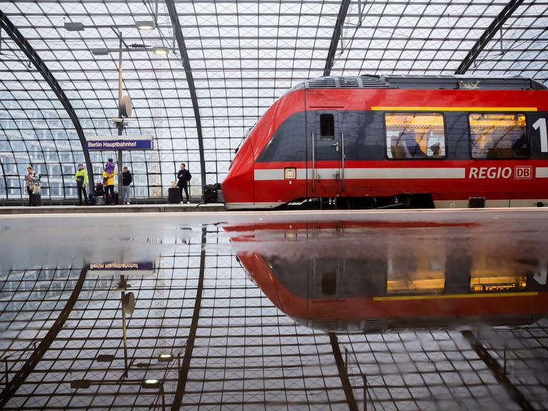 Ein Regionalzug fährt am Berliner Hauptbahnhof ein. Der Zug und die Halle spiegeln sich in einer Pfütze. (29.10.2023)
