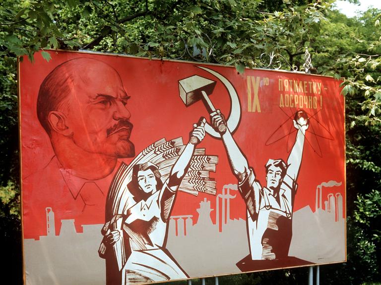 Ein großformatiges Plakat mit Lenin-Konterfei und der Darstellung von Arbeiter und Bäuerin mit Hammer und Sichel