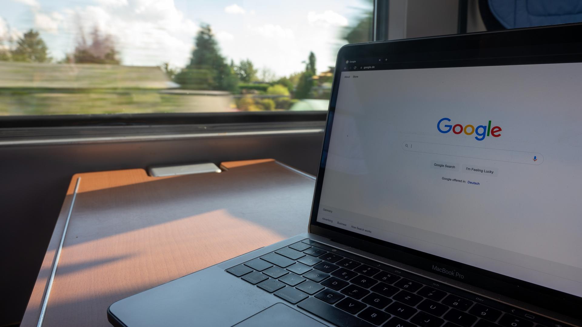 In einem Zug steht ein Laptop mit der Google-Homepage auf einem Tisch. In einem Zug steht ein Laptop mit der Google-Homepage auf einem Tisch.