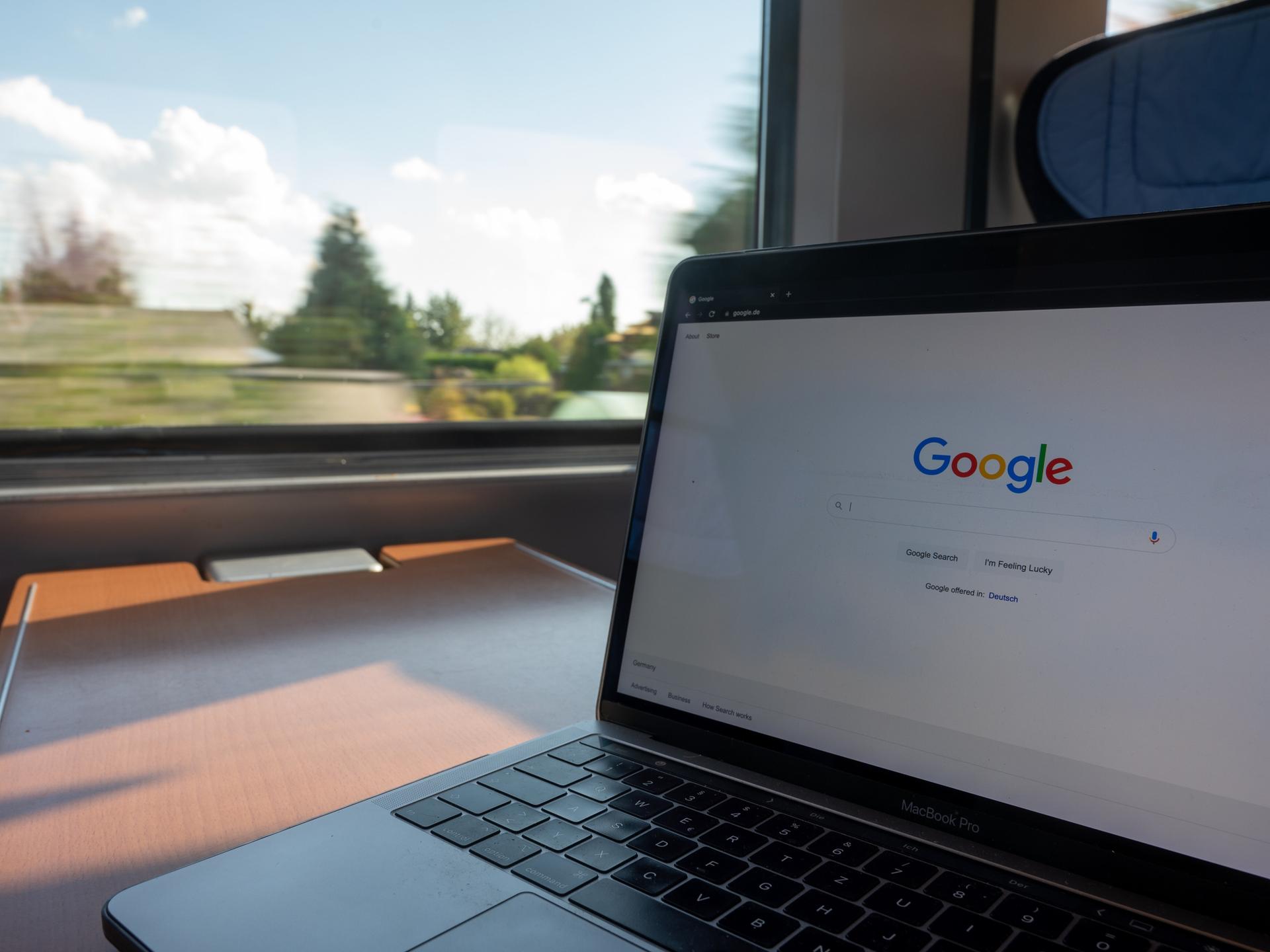 In einem Zug steht ein Laptop mit der Google-Homepage auf einem Tisch.