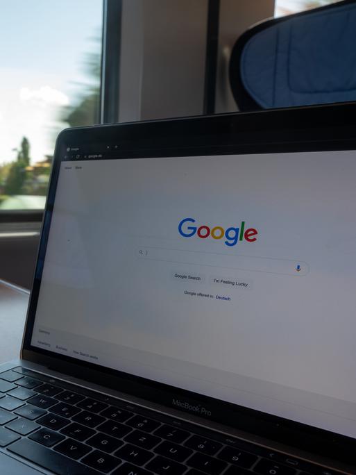In einem Zug steht ein Laptop mit der Google-Homepage auf einem Tisch. In einem Zug steht ein Laptop mit der Google-Homepage auf einem Tisch.
