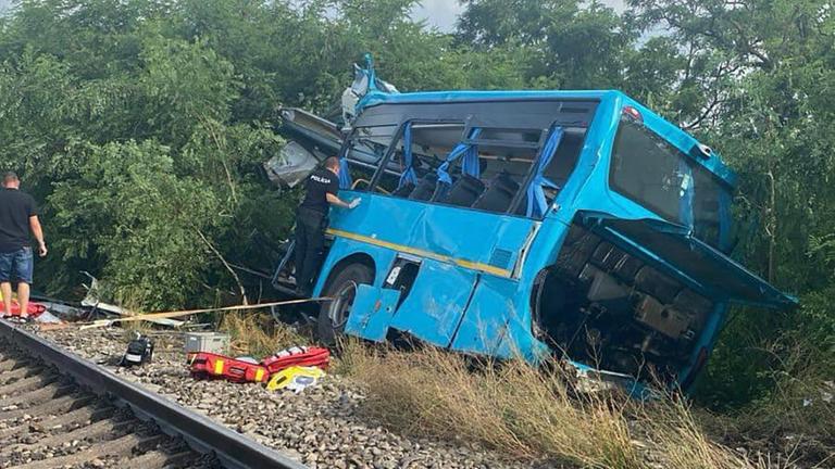 Ein hellblauer Bus liegt gekippt neben den Schienen im Schotter. Ein hellblauer Bus liegt gekippt neben den Schienen im Schotter.