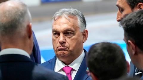 Viktor Orban steht umringt von anderen Politikern und schaut grimmig.