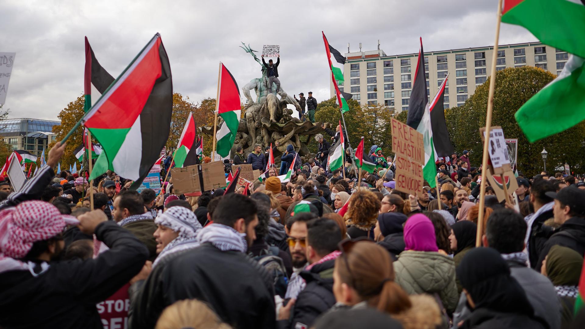 Eine Menschenmenge steht vor dem Berliner Neptunbrunnen. Viele tragen die palästinensische Flagge.
