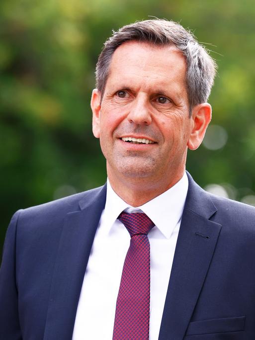 Der neue Ministerpräsident von Niedersachsen, Olaf Lies (SPD), im Anzug mit dunkelroter Krawatte vor grünem Hintergrund.