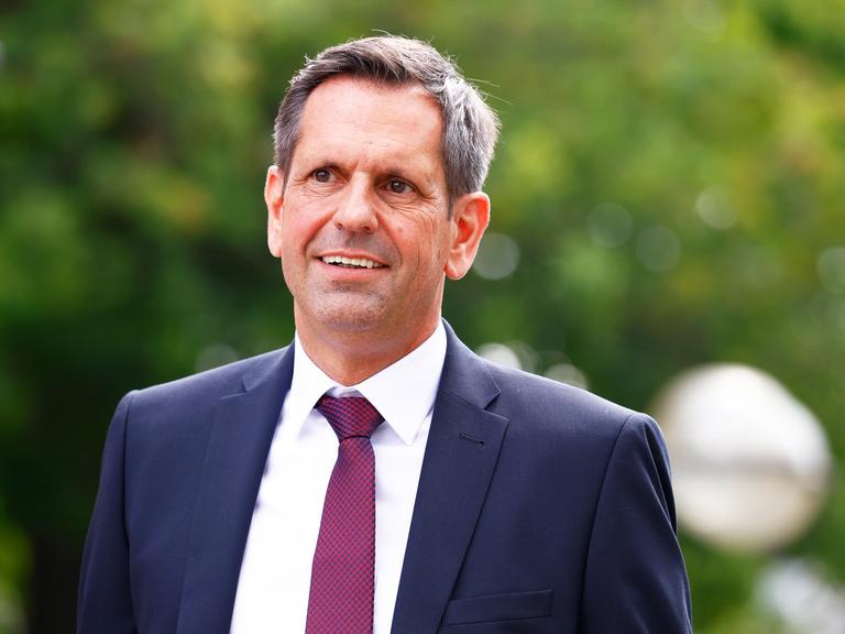 Der neue Ministerpräsident von Niedersachsen, Olaf Lies (SPD), im Anzug mit dunkelroter Krawatte vor grünem Hintergrund.