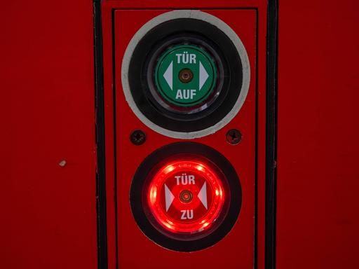 Ein Knopf mit der Aufschrift "Tür zu" leuchtet neben einer Zugtür der Deutschen Bahn.