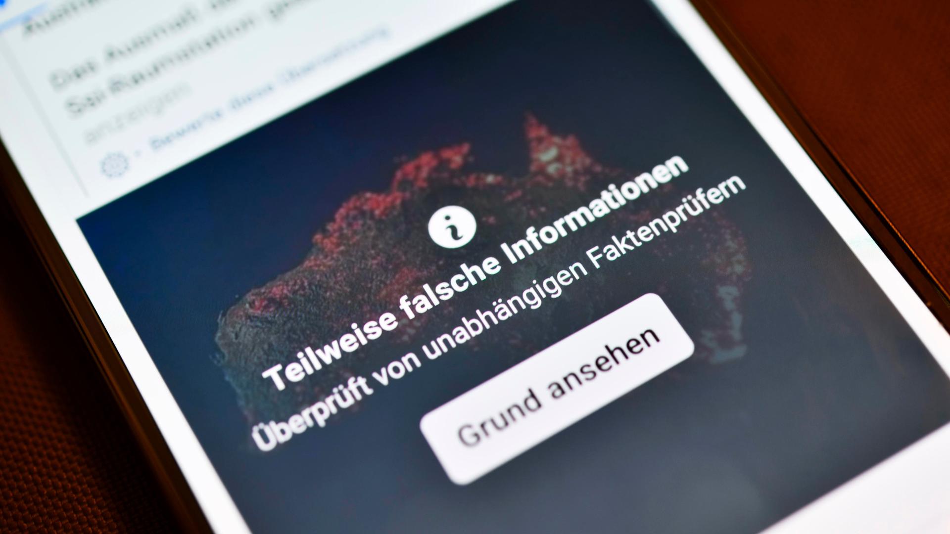 Smartphone mit aufgedeckter Falschinformation in einem sozialen Netzwerk